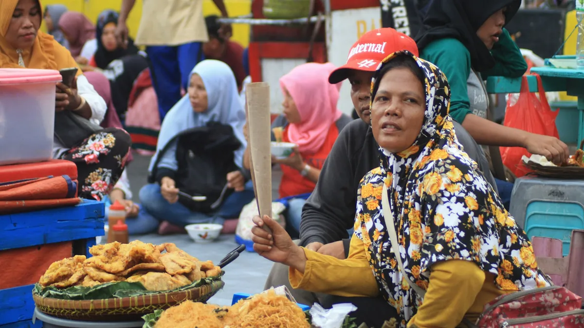 Penjual menyiapkan makanan pagi di kios sederhana