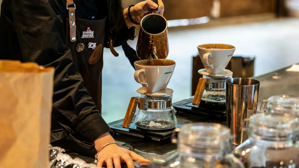 Barista menuang air panas ke atas kopi seduh manual