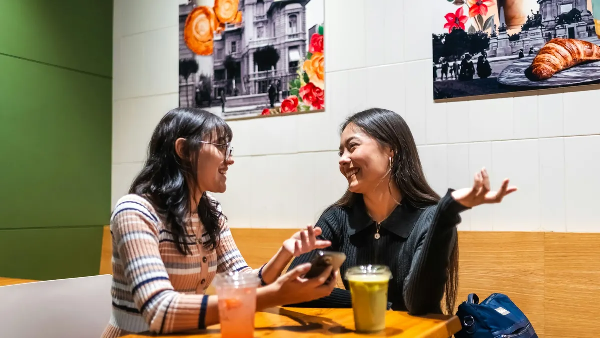 Dua orang mengobrol santai di meja kafe